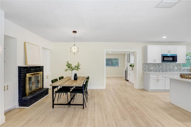 dining area with light hardwood / wood-style flooring and a brick fireplace