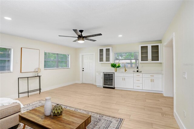 living room featuring sink, light wood-type flooring, beverage cooler, and ceiling fan