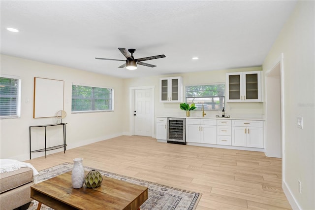 living room featuring recessed lighting, beverage cooler, light wood-style flooring, and baseboards