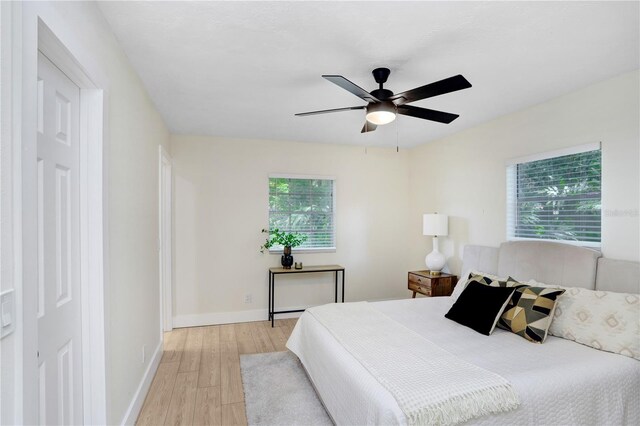 bedroom featuring ceiling fan, multiple windows, and light hardwood / wood-style floors