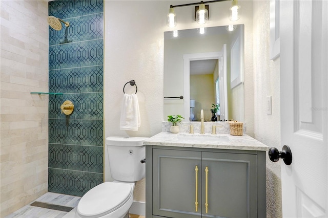 full bathroom featuring toilet, tiled shower, and vanity