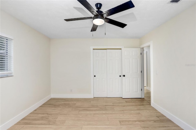 unfurnished bedroom with light wood-style floors, a closet, ceiling fan, and baseboards