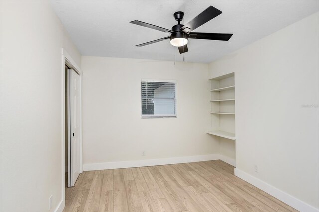 empty room with ceiling fan, light wood-type flooring, and built in features