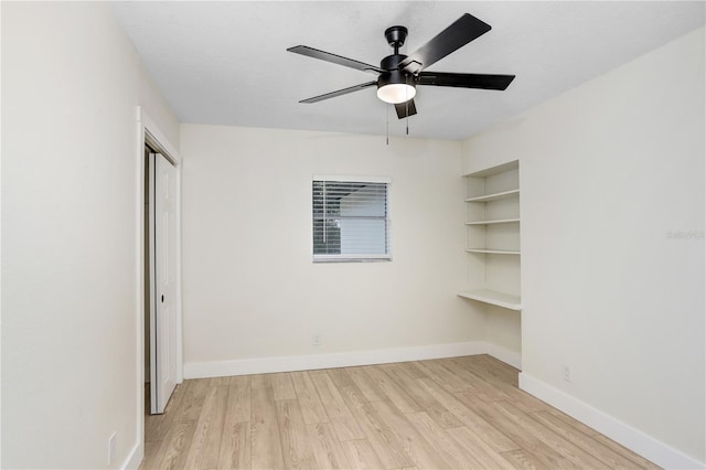 unfurnished room with light wood-style floors, ceiling fan, baseboards, and built in features