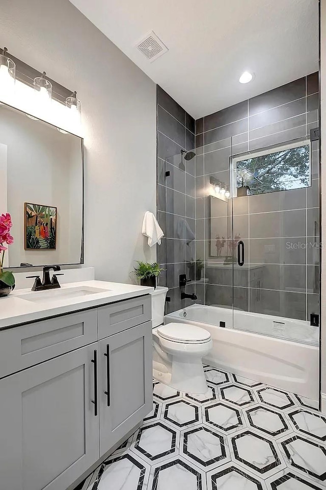 full bathroom featuring bath / shower combo with glass door, vanity, and toilet