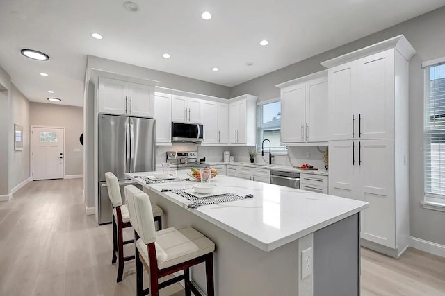 kitchen featuring stainless steel appliances, white cabinetry, sink, and a center island