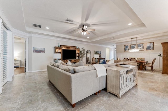 living room with ceiling fan, crown molding, light wood-type flooring, and a tray ceiling