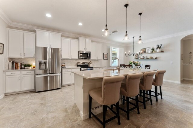 kitchen with white cabinets, a center island with sink, stainless steel appliances, and a kitchen breakfast bar