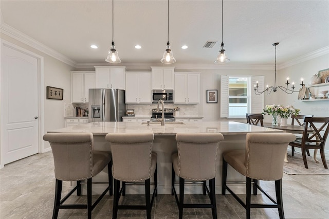 kitchen with appliances with stainless steel finishes, pendant lighting, light stone counters, and a large island