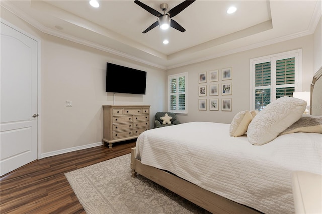 bedroom featuring ceiling fan, dark wood-type flooring, ornamental molding, and a tray ceiling