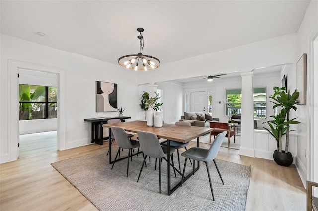 dining area featuring ceiling fan with notable chandelier, light wood-type flooring, and decorative columns