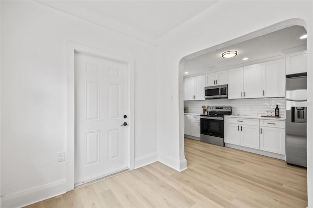 kitchen featuring tasteful backsplash, light hardwood / wood-style flooring, appliances with stainless steel finishes, and white cabinetry