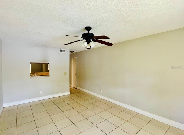 tiled empty room featuring ceiling fan and a textured ceiling