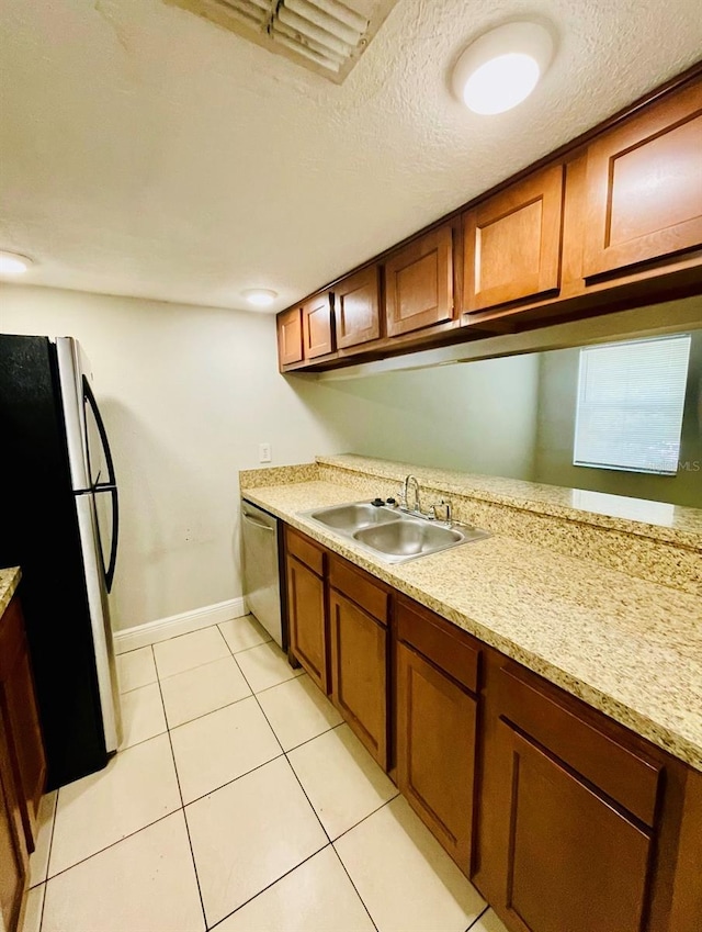 kitchen with sink, stainless steel appliances, a textured ceiling, and light tile patterned flooring