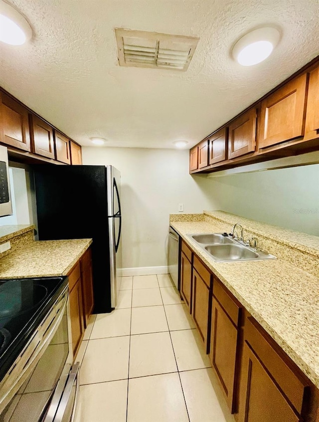 kitchen with light tile patterned flooring, stainless steel appliances, sink, and a textured ceiling