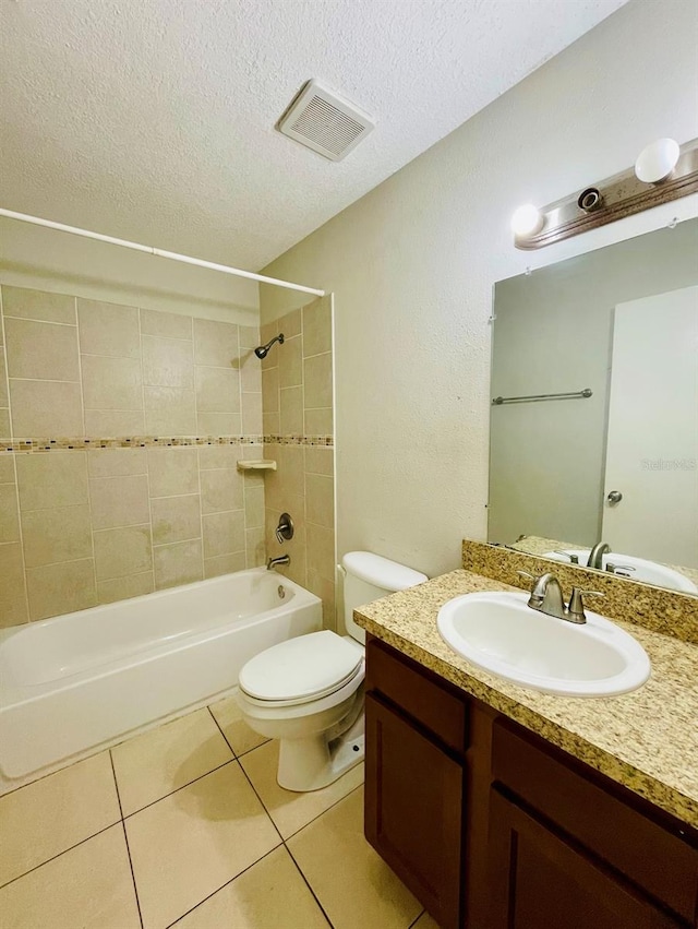 full bathroom with a textured ceiling, toilet, tiled shower / bath, tile patterned floors, and vanity