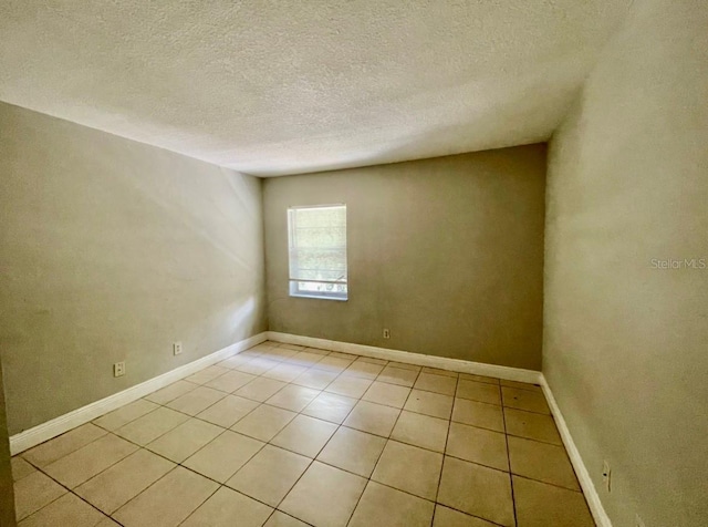 unfurnished room with light tile patterned flooring and a textured ceiling