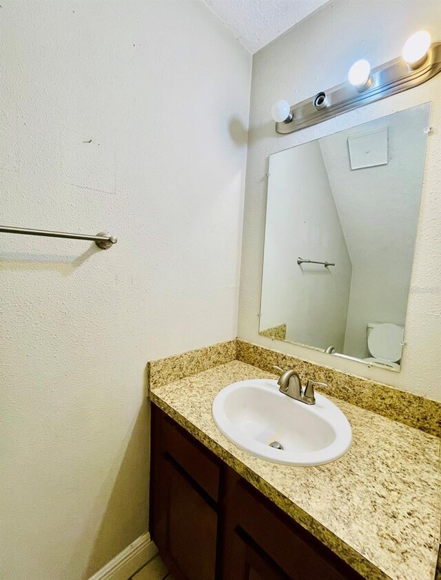 bathroom featuring a textured ceiling, vanity, and toilet