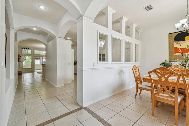 tiled dining space with decorative columns and a notable chandelier