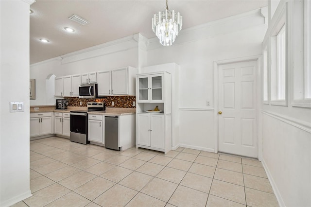 kitchen featuring pendant lighting, white cabinets, light tile patterned floors, ornamental molding, and appliances with stainless steel finishes