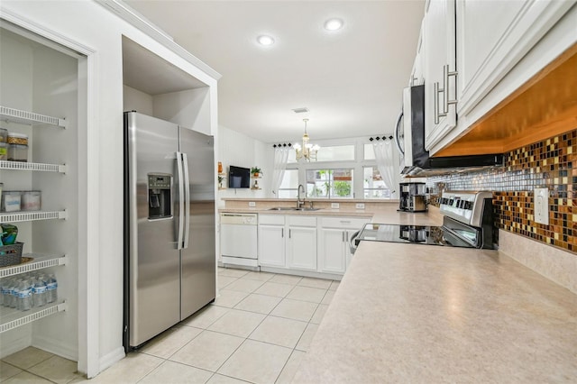 kitchen featuring appliances with stainless steel finishes, sink, light tile patterned floors, pendant lighting, and white cabinets