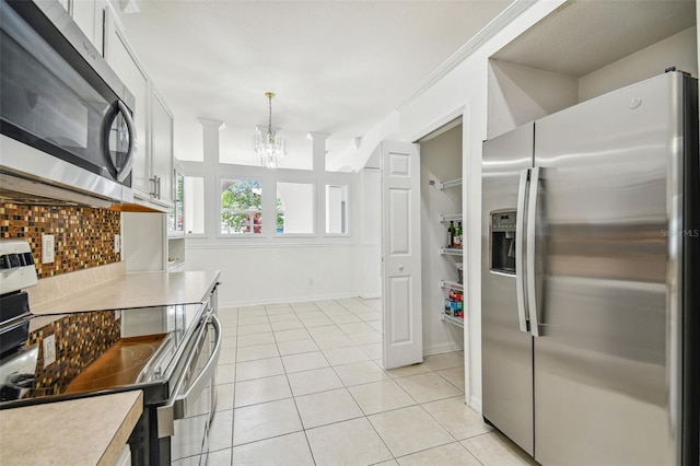 kitchen featuring appliances with stainless steel finishes, light tile patterned floors, a chandelier, white cabinetry, and hanging light fixtures