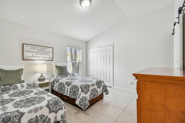 bedroom with a closet, light tile patterned floors, and vaulted ceiling