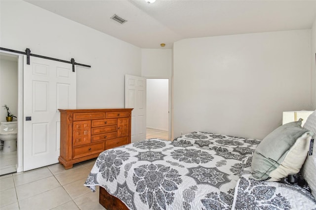 bedroom with ensuite bathroom, a barn door, light tile patterned floors, and lofted ceiling