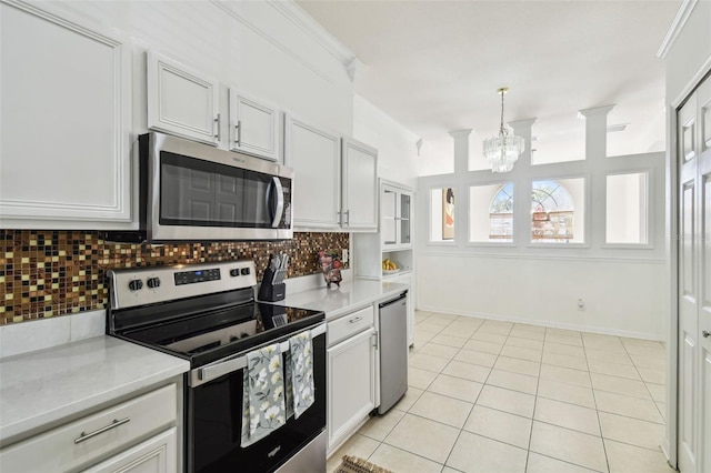 kitchen featuring light tile patterned floors, light countertops, backsplash, appliances with stainless steel finishes, and a chandelier