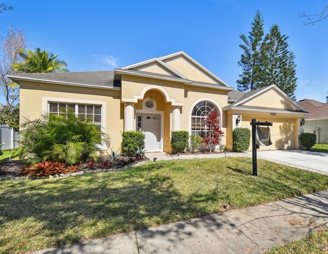 view of front of property featuring concrete driveway, a front yard, stucco siding, and an attached garage