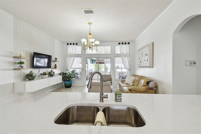 kitchen with a chandelier, a sink, light countertops, and visible vents