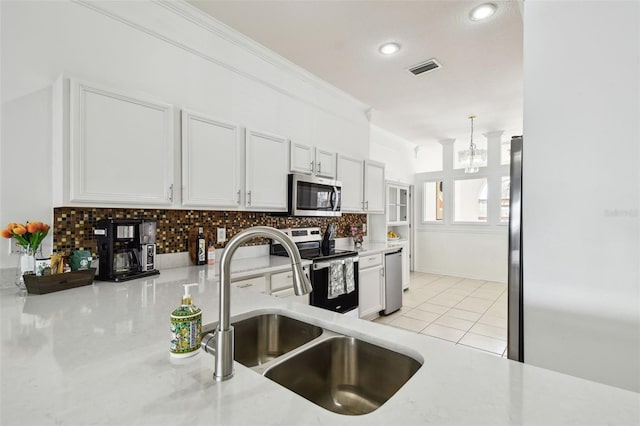 kitchen with light tile patterned floors, ornamental molding, appliances with stainless steel finishes, a sink, and decorative backsplash