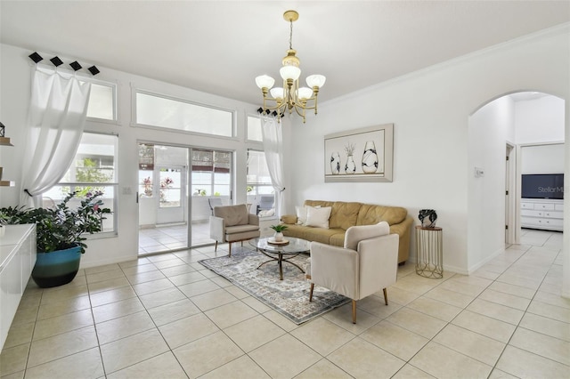 living area featuring a notable chandelier, baseboards, crown molding, light tile patterned flooring, and arched walkways