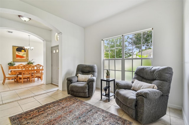 living area with visible vents, baseboards, arched walkways, a notable chandelier, and light tile patterned flooring