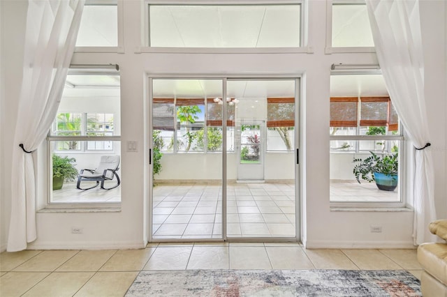 doorway to outside featuring tile patterned floors, plenty of natural light, and baseboards