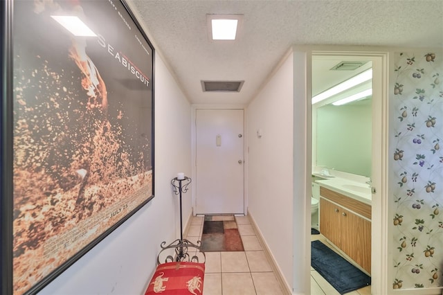 hall with sink, a textured ceiling, and tile patterned flooring