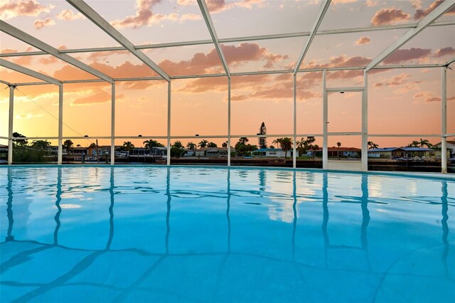 pool at dusk featuring glass enclosure