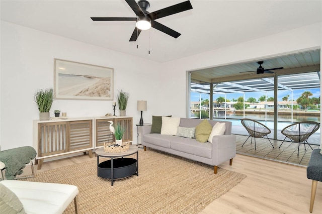 living room with a water view, ceiling fan, and hardwood / wood-style floors