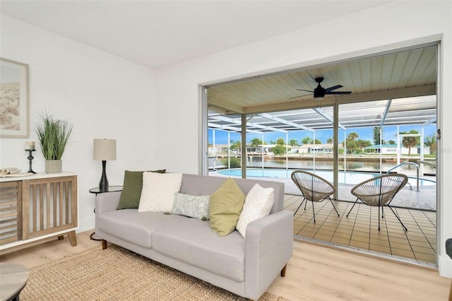 living room with ceiling fan, light wood-type flooring, plenty of natural light, and a water view