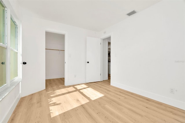 unfurnished bedroom with a spacious closet, light hardwood / wood-style floors, and a closet