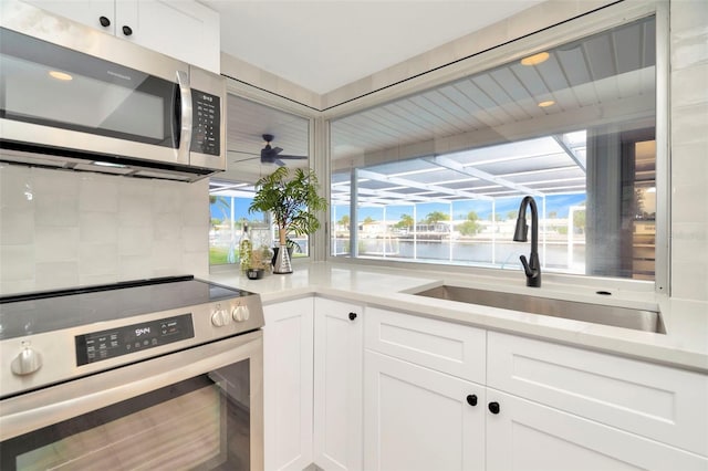 kitchen featuring sink, white cabinets, ceiling fan, stainless steel appliances, and a water view