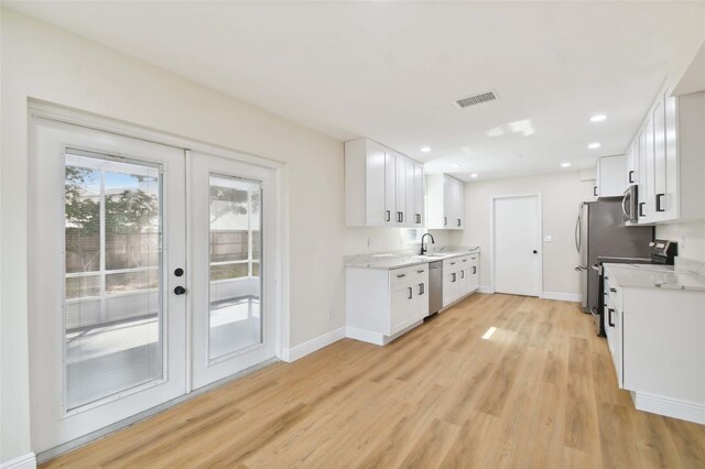 kitchen featuring light wood-type flooring, appliances with stainless steel finishes, sink, and white cabinets