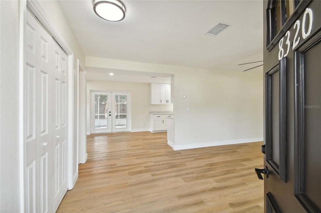 foyer with light wood finished floors, baseboards, visible vents, and french doors