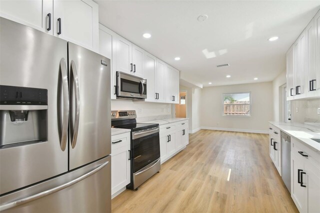 kitchen with stainless steel appliances, white cabinets, and light stone counters