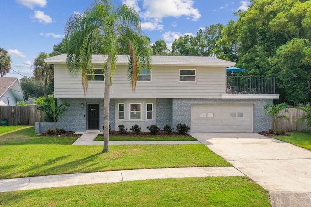 view of front facade featuring a garage, driveway, brick siding, fence, and a front yard