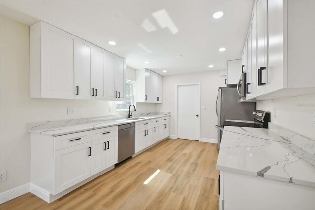 kitchen with white cabinetry, sink, light stone countertops, and appliances with stainless steel finishes