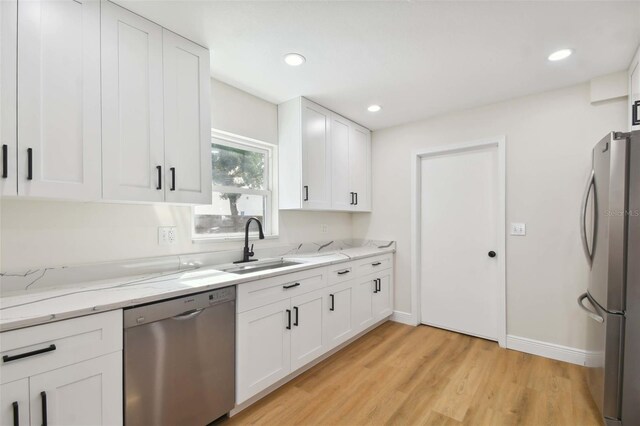 kitchen with sink, light stone countertops, white cabinets, and appliances with stainless steel finishes