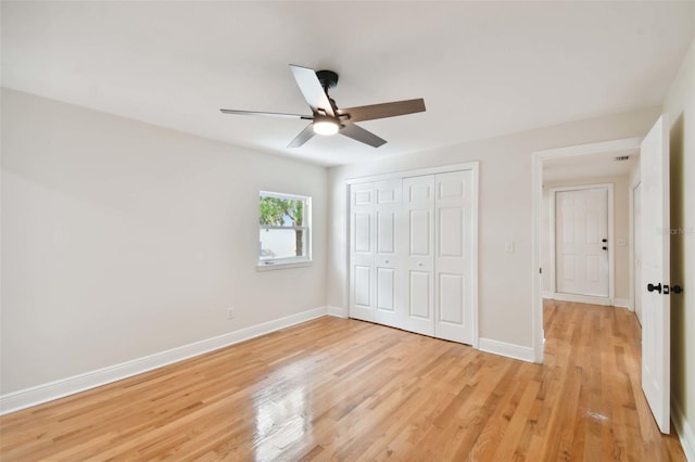 unfurnished bedroom featuring a ceiling fan, a closet, light wood-style flooring, and baseboards