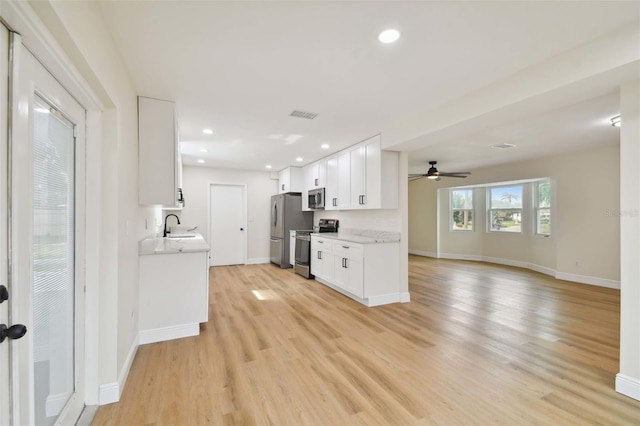 kitchen featuring appliances with stainless steel finishes, light wood-type flooring, light countertops, and a sink