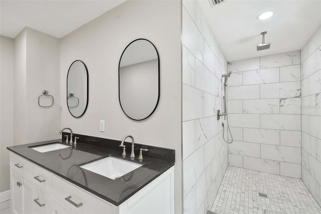 full bathroom featuring tiled shower, a sink, visible vents, and double vanity